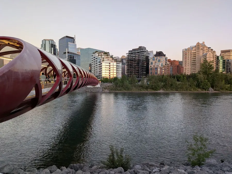 The red Peace Bridge crossing the Bow River at dusk with Calgary apartment towers behind